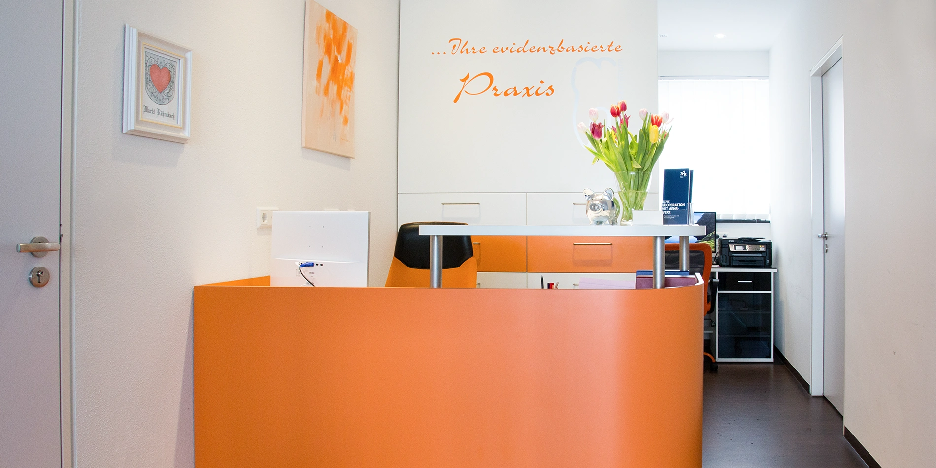 Empfangstresen der Zahnarztpraxis Dr. Raicov in Röhrnbach mit Blumenstrauß und Praxis-Schriftzug