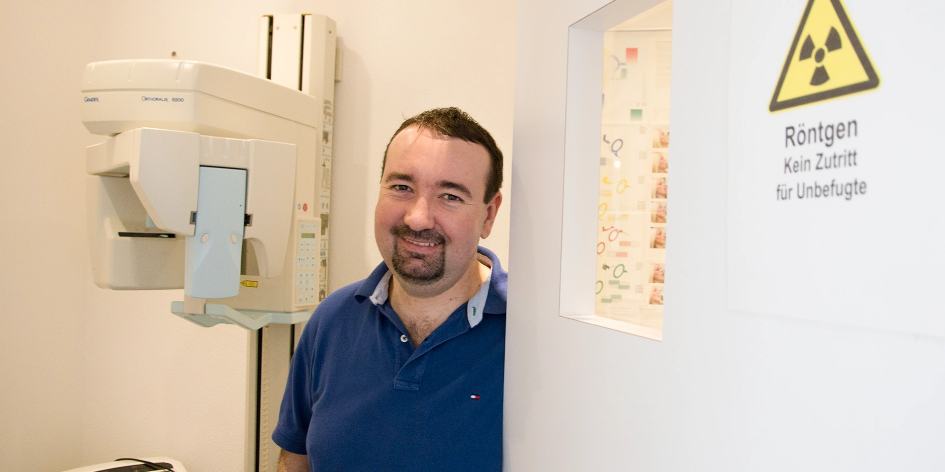 Dr. Raicov neben dem digitalen Röntgengerät der Zahnarztpraxis in Röhrnbach, daneben Warnschild "Röntgen – Kein Zutritt für Unbefugte"